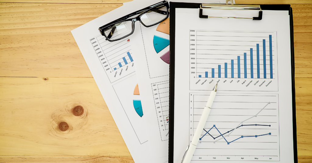 Graphs and tables on paper attached to a clipboard.