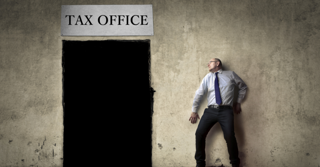 man standing against wall looking at avoiding door with tax office sign hanging above.