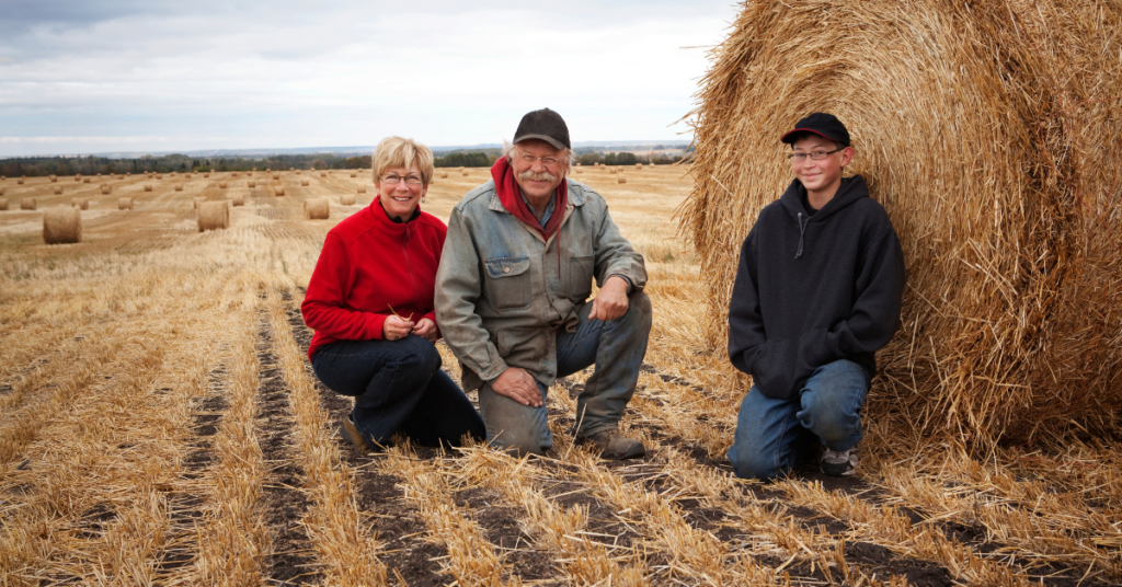 family on farm next to hay bale